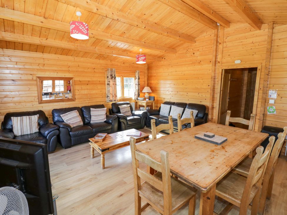 A living room with leather sofas and a wooden table at Oak Lodge in Offenham
