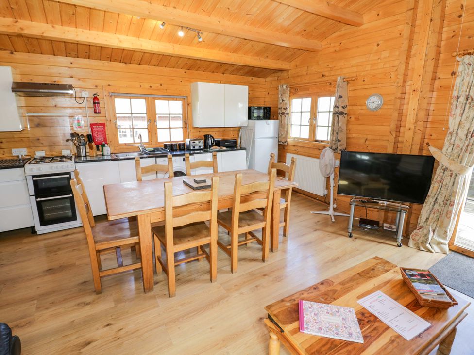 A kitchen with a wooden dining table and appliances at Oak Lodge Offenham