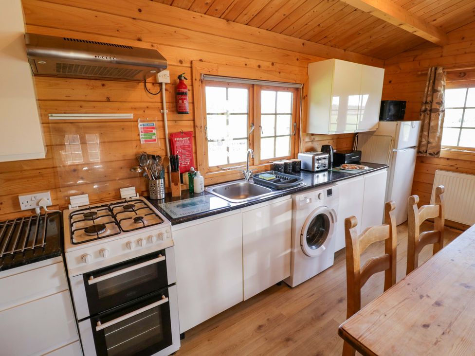 A kitchen with appliances and wooden furniture at Oak Lodge in Offenham