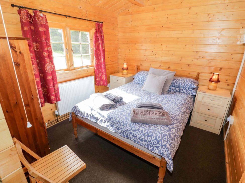 A bedroom with a double bed and wooden furniture at Oak Lodge Offenham