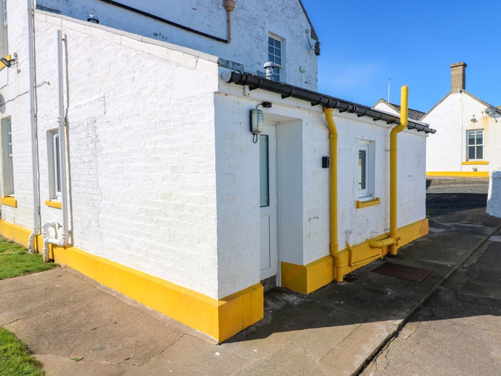 An exterior view of a white building with yellow trim at The Lighthouse Bothy St Abbs