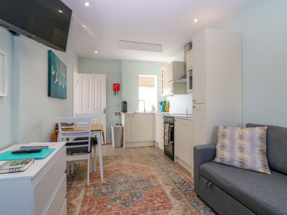 A living room with a sofa and kitchen area at The Lighthouse Bothy in St Abbs
