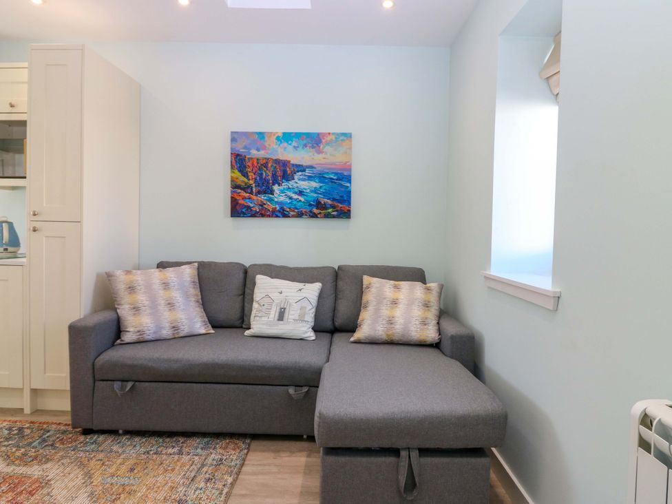 A living room with a sofa and artwork at The Lighthouse Bothy in St Abbs