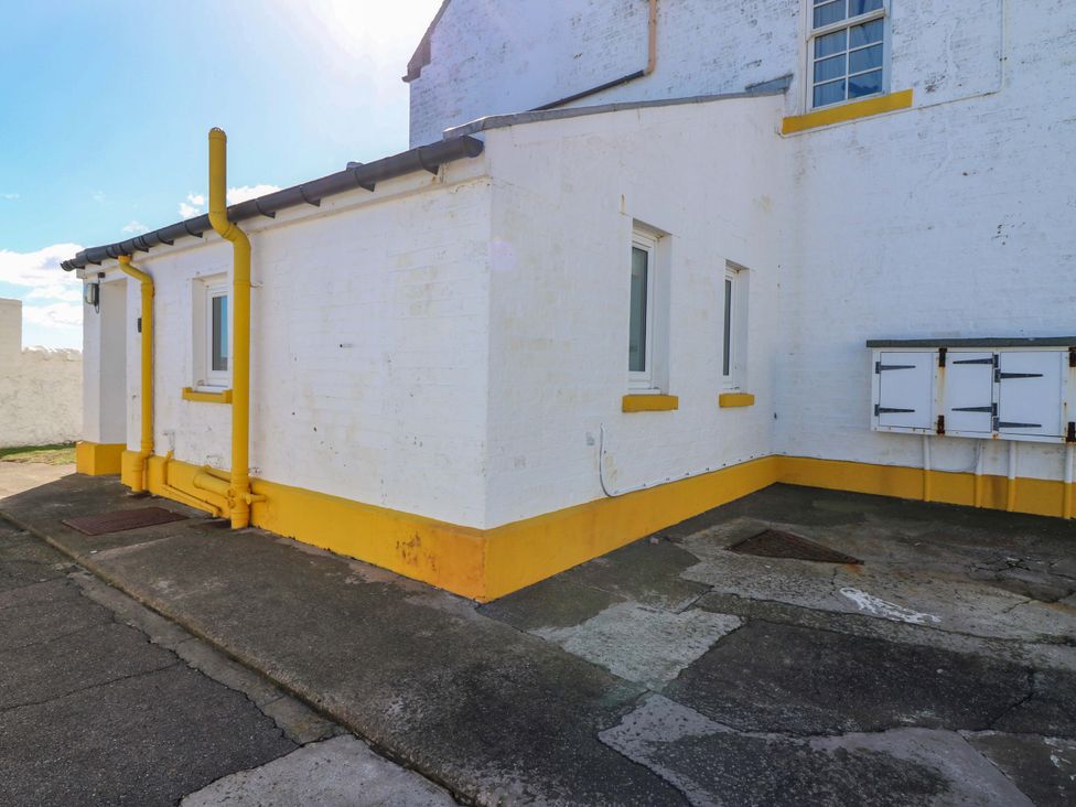 An outdoor area with a building and yellow pipes at The Lighthouse Bothy St Abbs