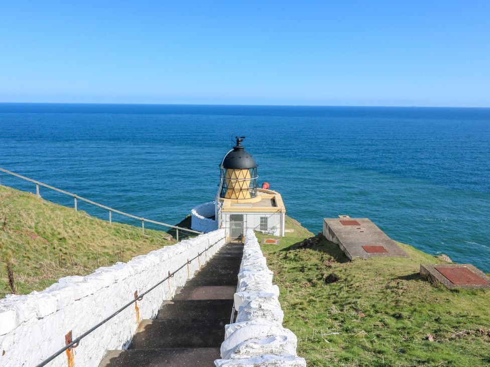 A lighthouse overlooking the ocean with steps leading down at The Lighthouse Bothy in St Abbs