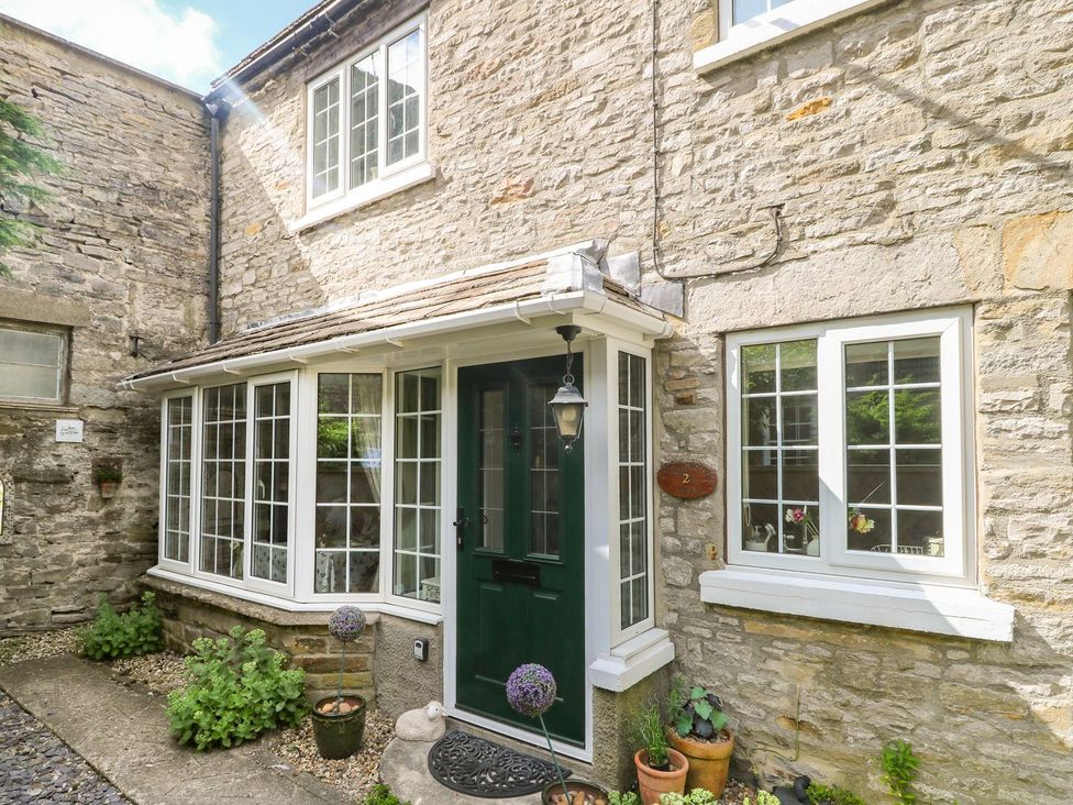An exterior view of a house with a green door and windows at Wedgewood Cottage in Middleham