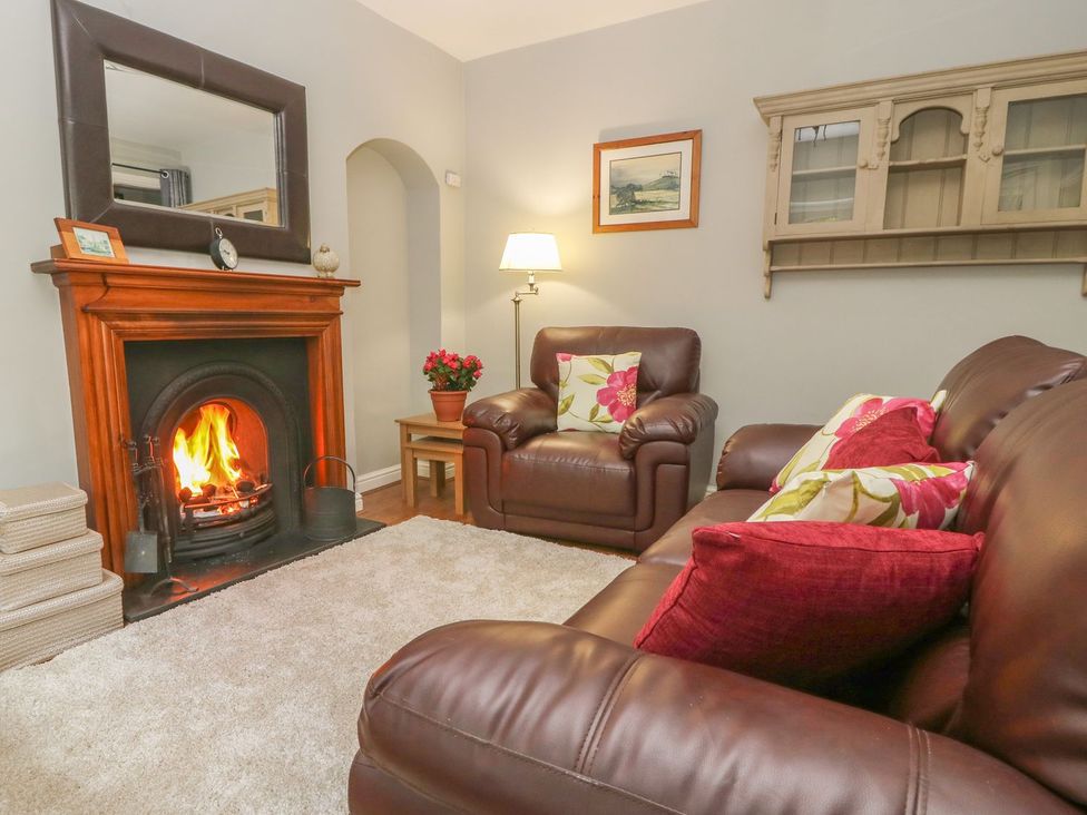 A living room with a fireplace and sofa at Wedgewood Cottage in Middleham
