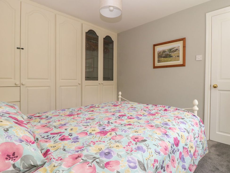 A bedroom with a bed and wardrobe at Wedgewood Cottage in Middleham