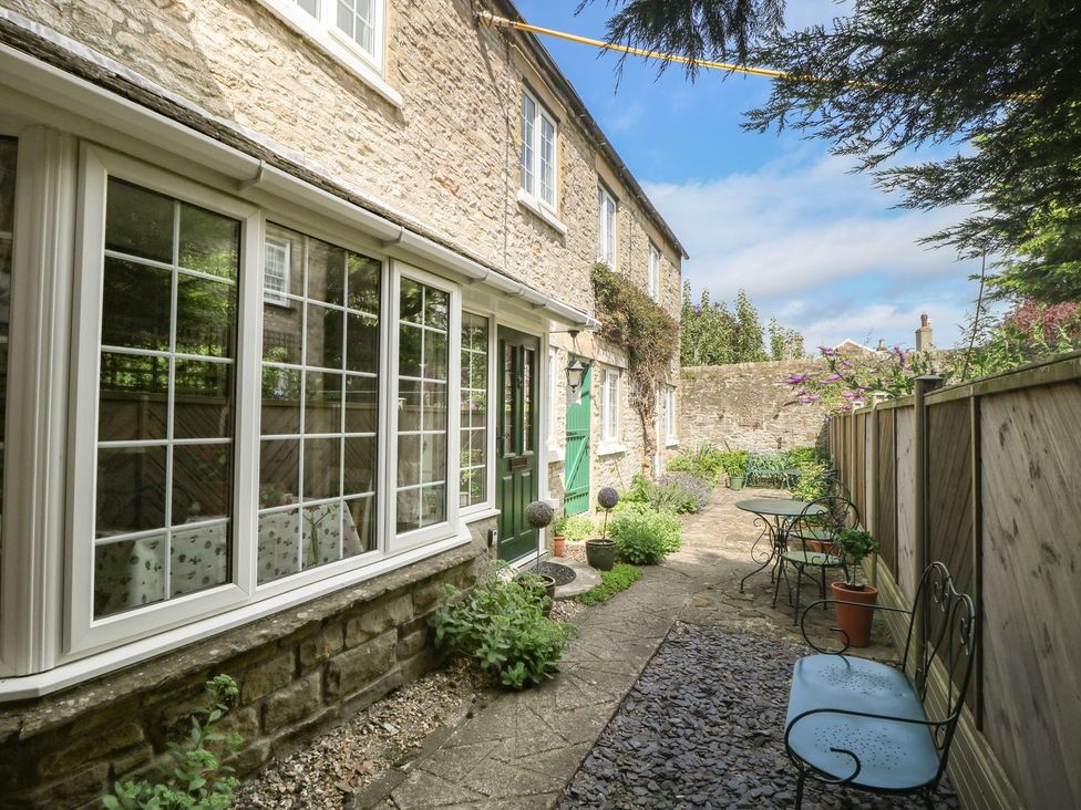 A garden with stone walls and seating area at Wedgewood Cottage in Middleham