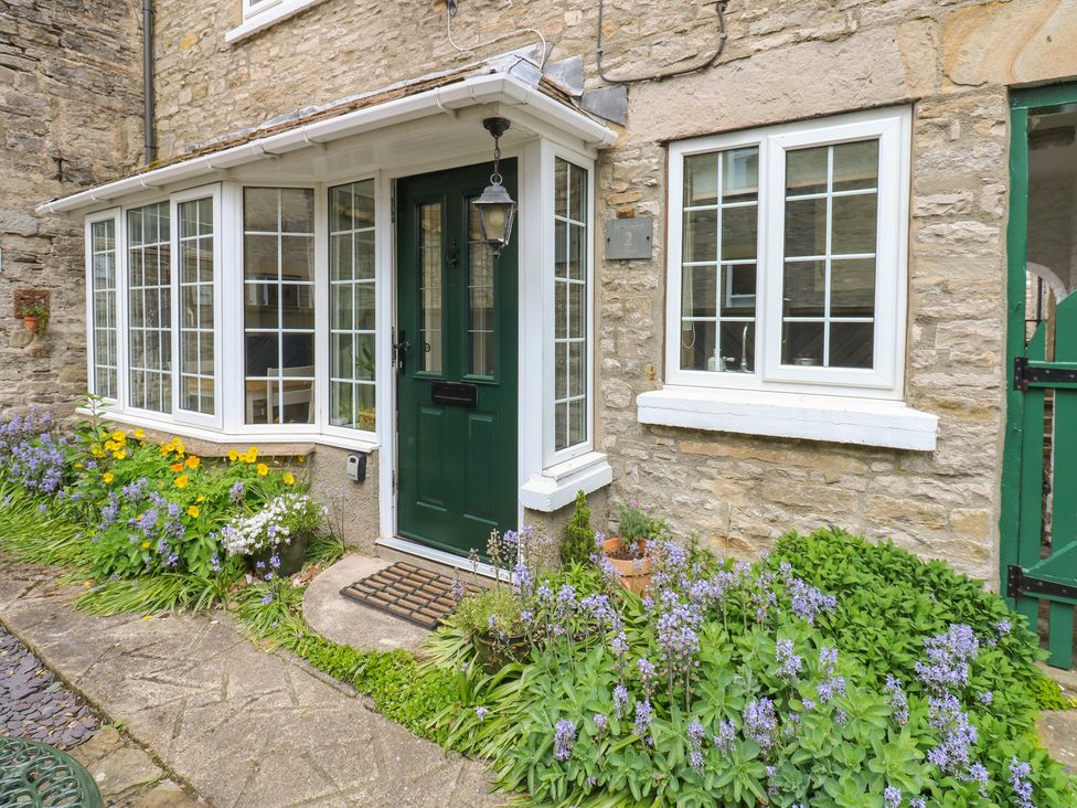 An entrance with a green door and windows at Wedgewood Cottage in Middleham