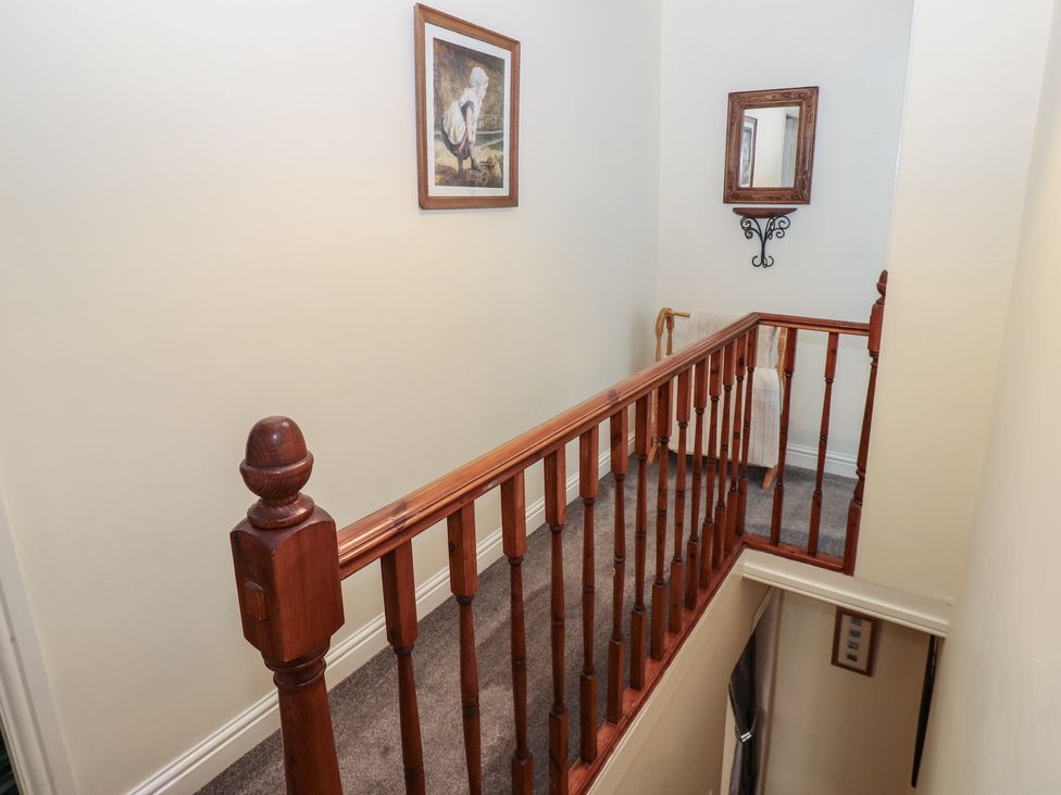 A hallway with a stair railing and wall decor at Wedgewood Cottage in Middleham
