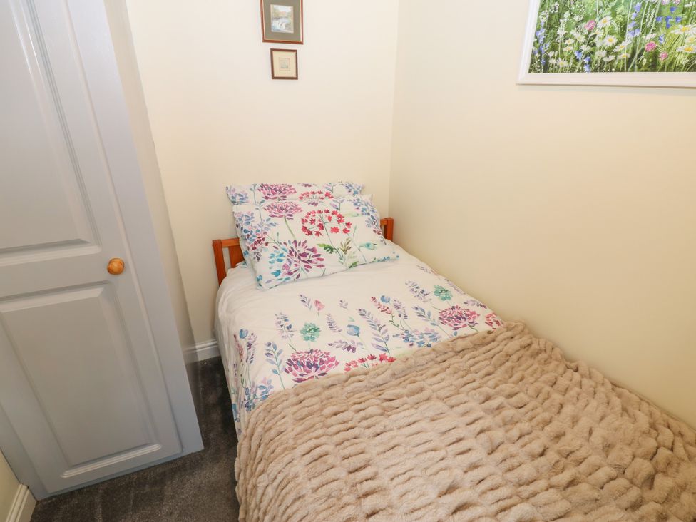 A single bed with floral bedding in a bedroom at Wedgewood Cottage in Middleham