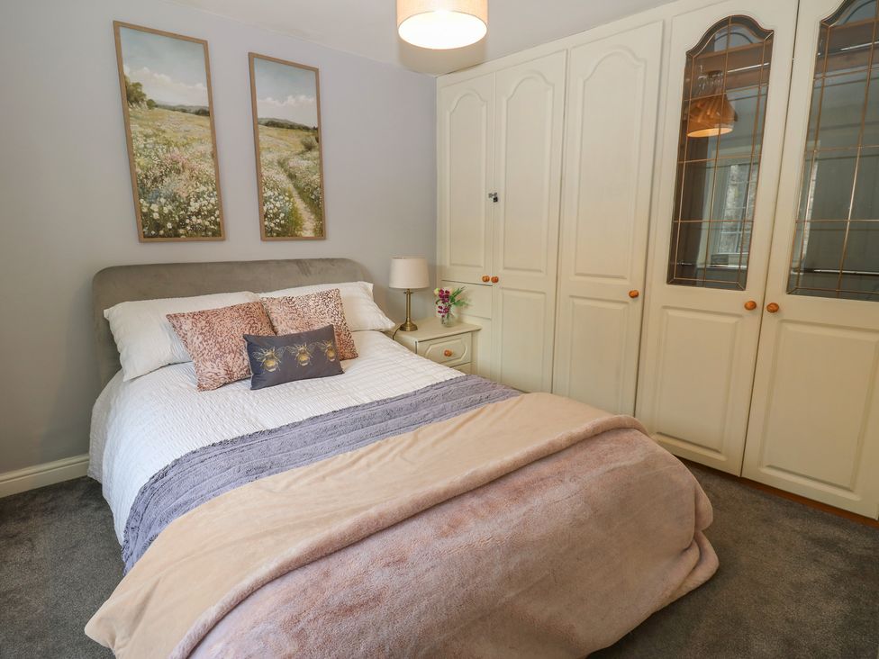 A bedroom with a bed and wardrobe at Wedgewood Cottage in Middleham