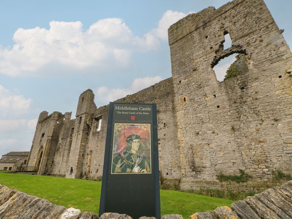 Castle ruins with an informational sign at Middleham Castle in Middleham