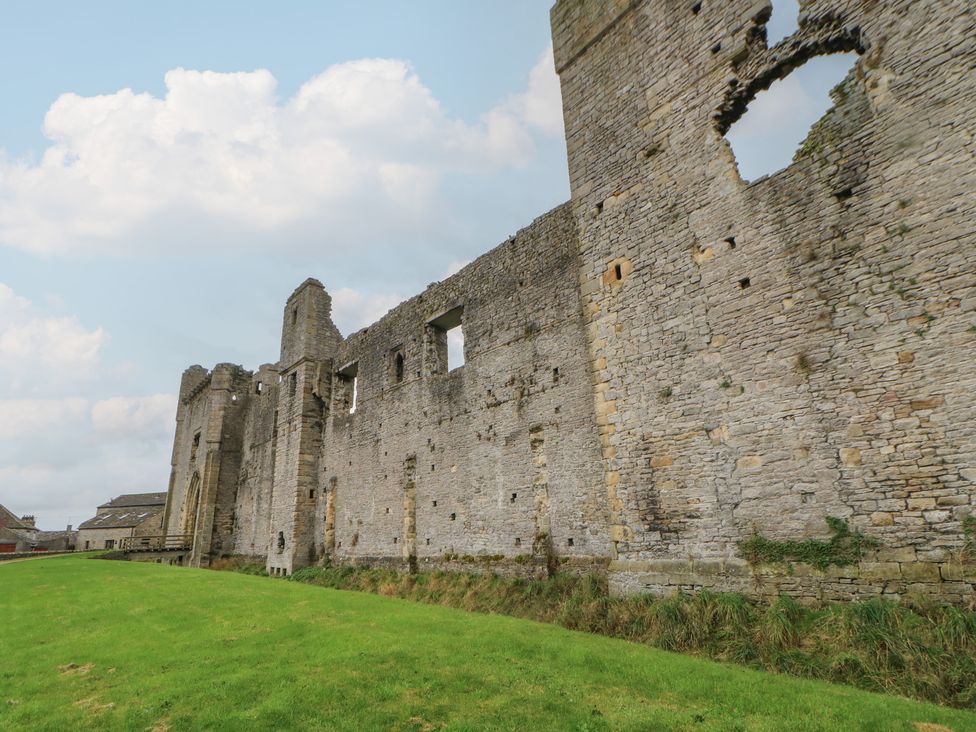 A view of a stone ruin with windows and grass at Wedgewood Cottage in Middleham