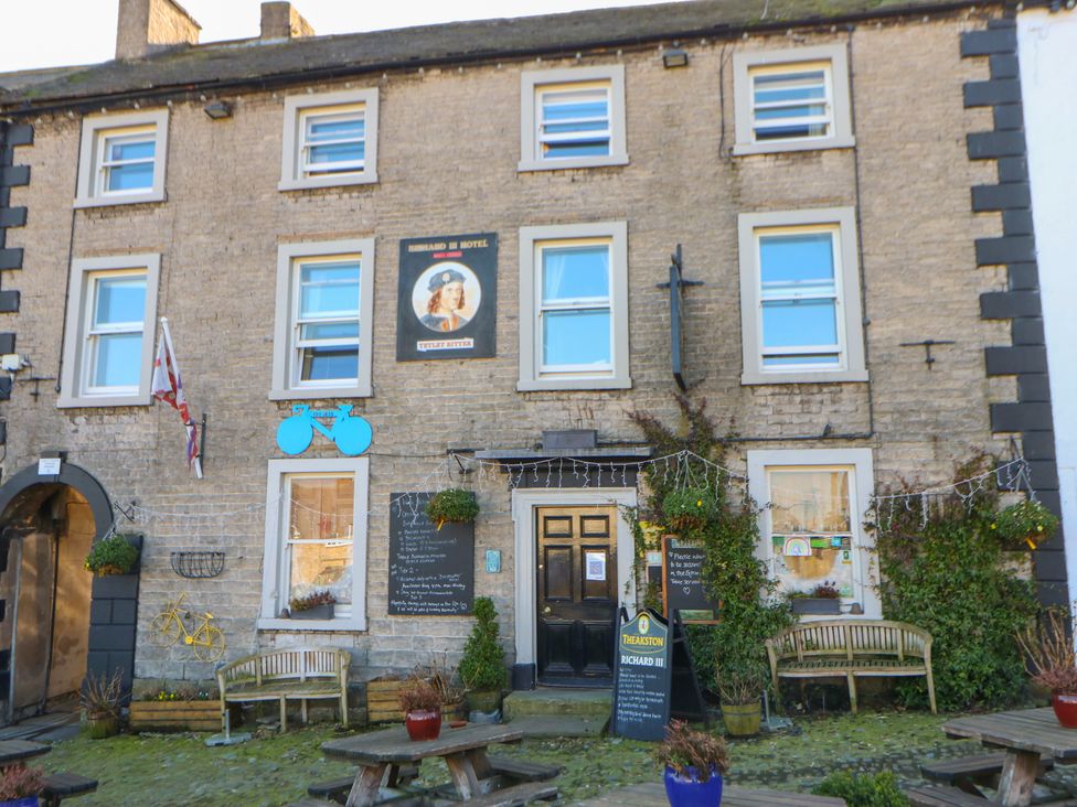 A hotel exterior with a sign and benches at Wedgewood Cottage in Middleham