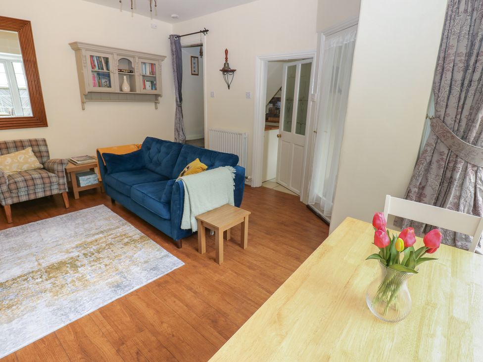 A living room with a sofa, armchair, and dining table at Wedgewood Cottage in Middleham