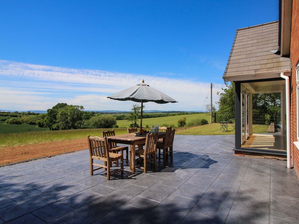 A patio with a table and chairs under an umbrella at Westington Hall Hatfield near Bromyard