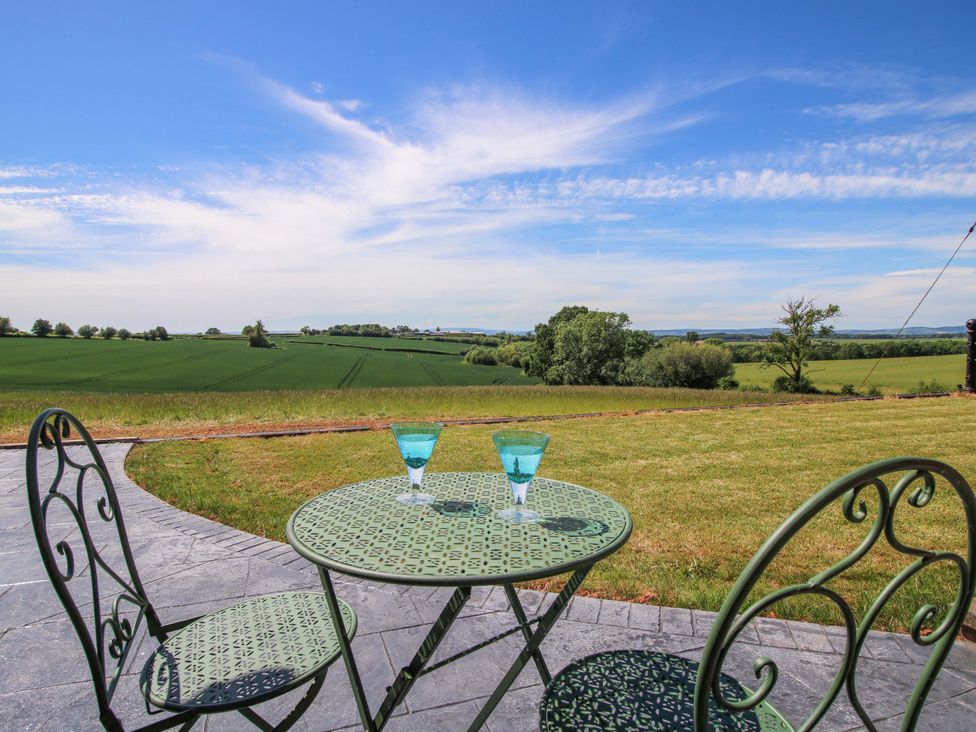 An outdoor area with a table and glasses overlooking fields at Westington Hall Hatfield near Bromyard