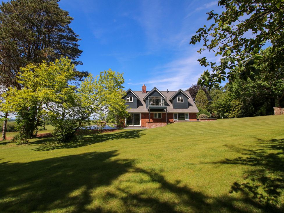 A house with a large lawn and trees at Westington Hall in Hatfield near Bromyard