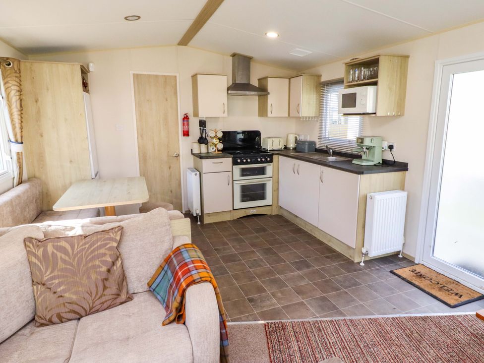 A kitchen area with appliances and seating at Sunflower Retreat, Caravan 61
