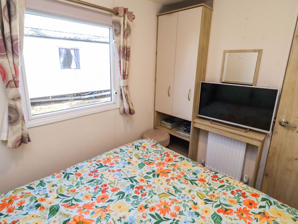 A bedroom with a bed, television, and wardrobe at Sunflower Retreat, Caravan 61