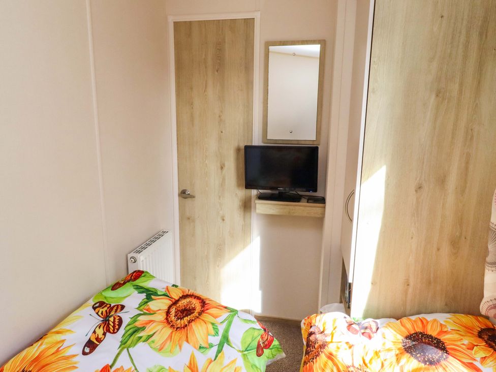 A bedroom with a door, TV and mirror at Sunflower Retreat, Caravan 61