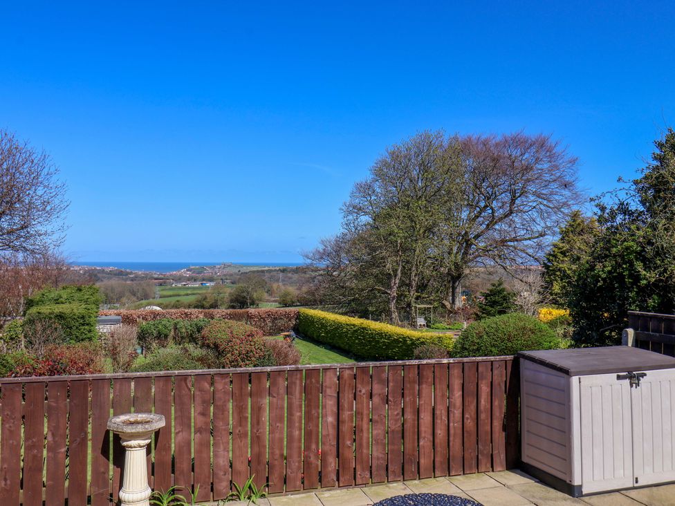 A garden with trees and a view of the sea at Annie's Place in Sleights