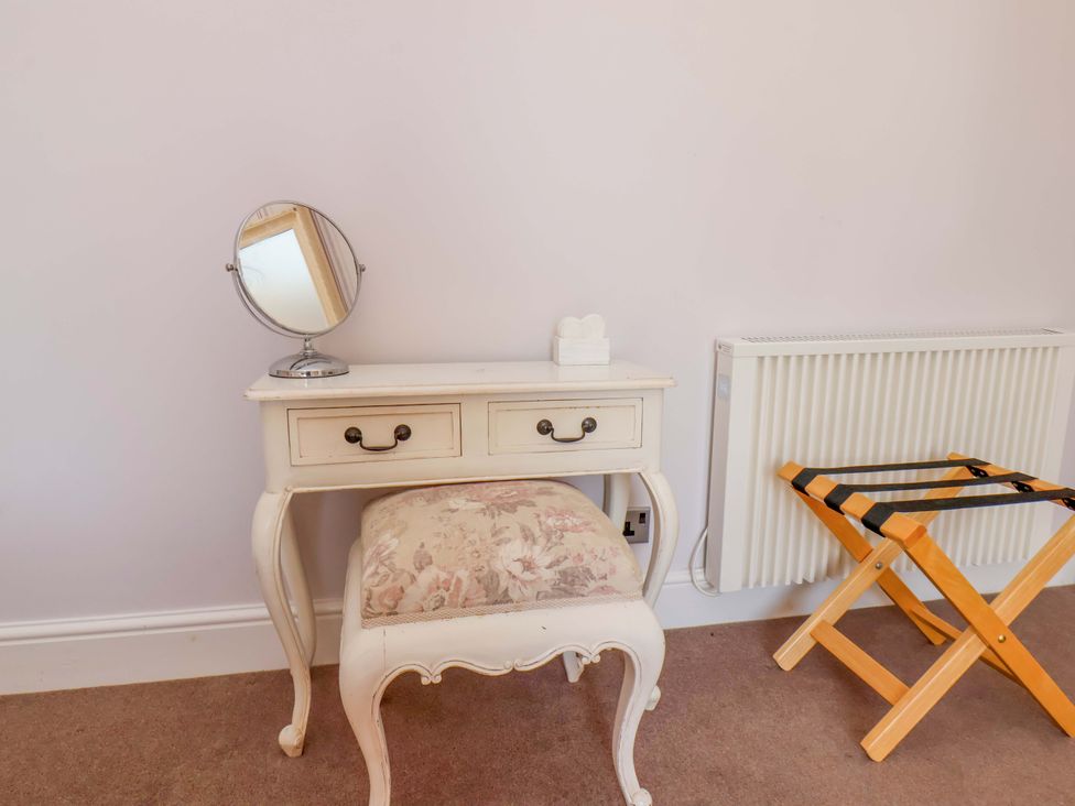 A vanity table with a mirror and stool in a bedroom at Annie's Place in Sleights