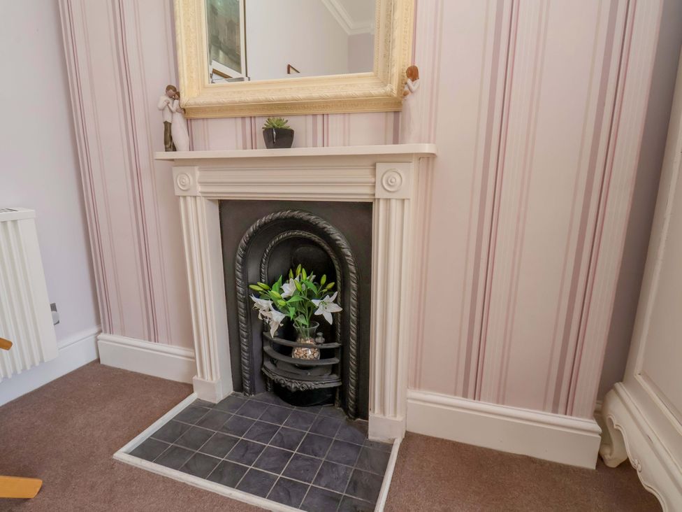 A fireplace with flowers and a mirror at Annie's Place in Sleights