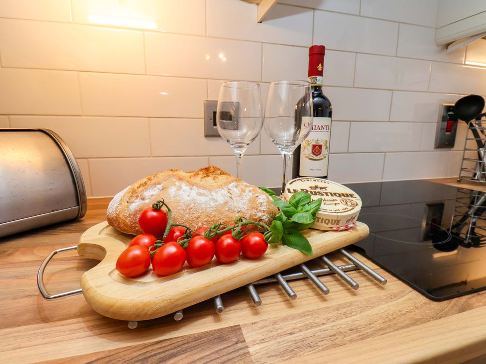 A kitchen with bread, tomatoes, wine, and cheese on a cutting board at Annie's Place in Sleights