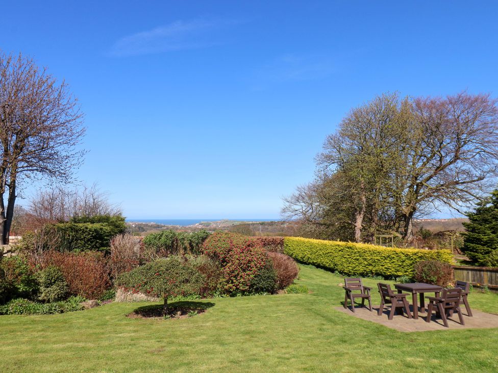 A garden with grass, trees, and a view of the sea at Annie's Place in Sleights