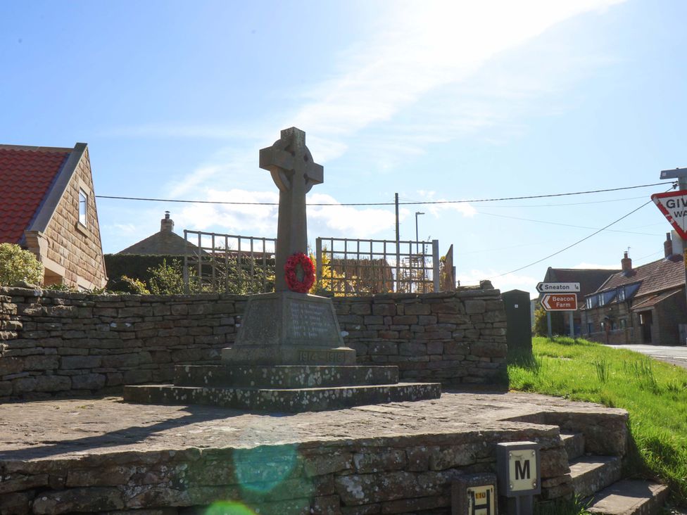 A war memorial with a cross and wreath at Annie's Place in Sleights