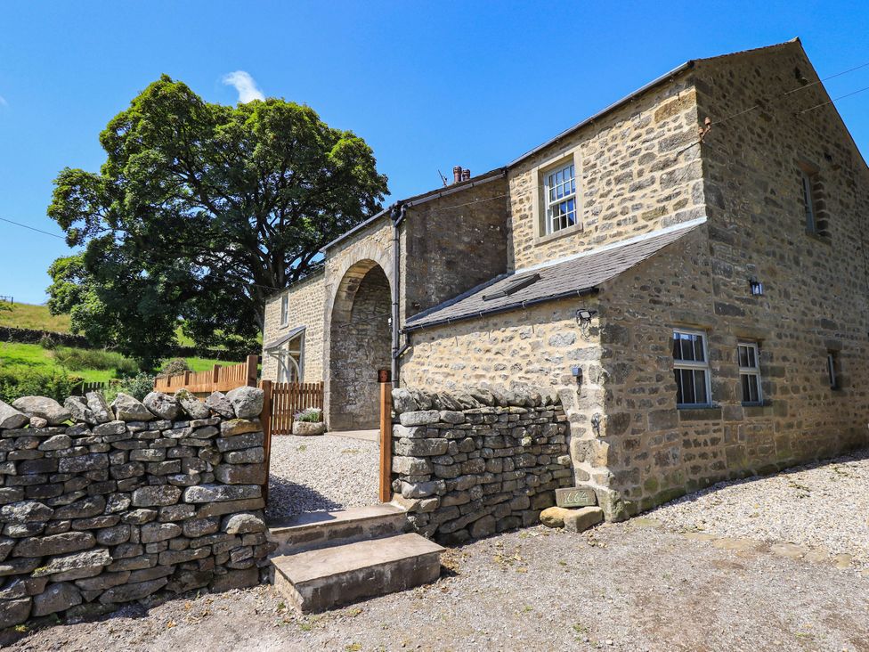 A house with a stone wall and tree in front at Ragged Hall Barn Settle