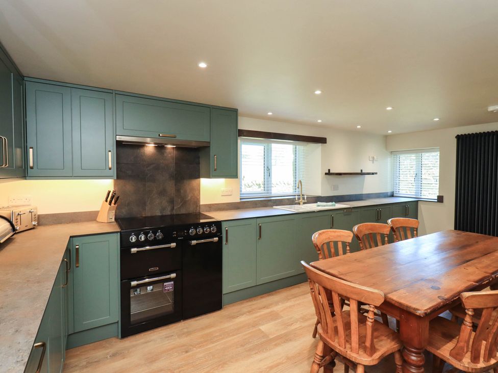 A kitchen with cabinets and a dining table at Ragged Hall Barn in Settle