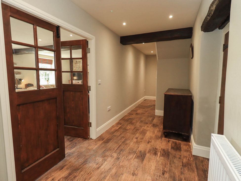 A hallway with wooden flooring and a cabinet at Ragged Hall Barn Settle