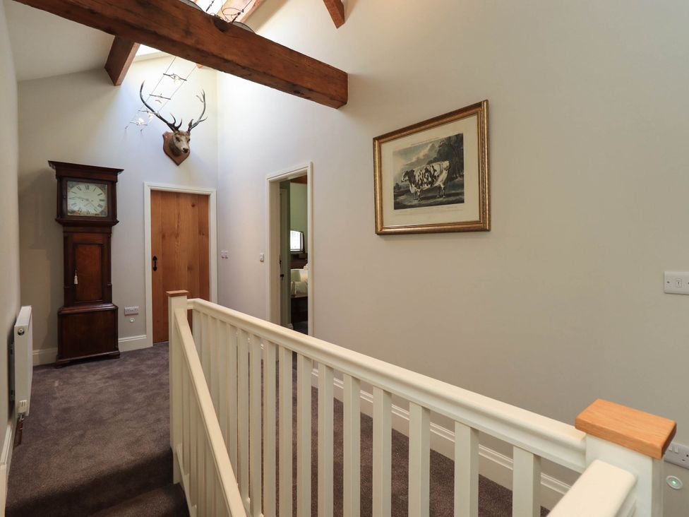 A hallway with a clock, artwork and deer head at Ragged Hall Barn Settle