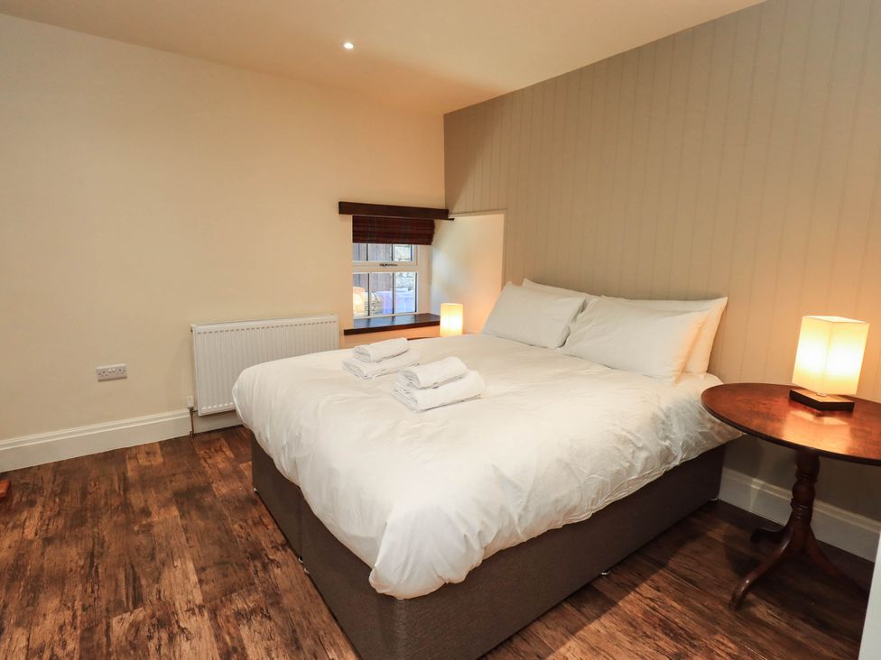 A bedroom with a bed and nightstand at Ragged Hall Barn Settle