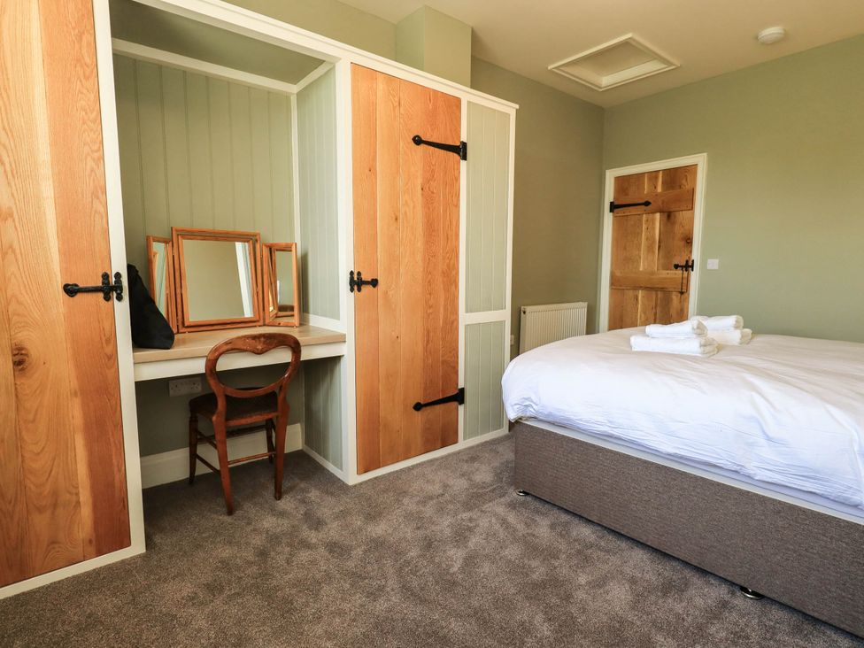 A bedroom with a bed and a desk with a mirror at Ragged Hall Barn Settle