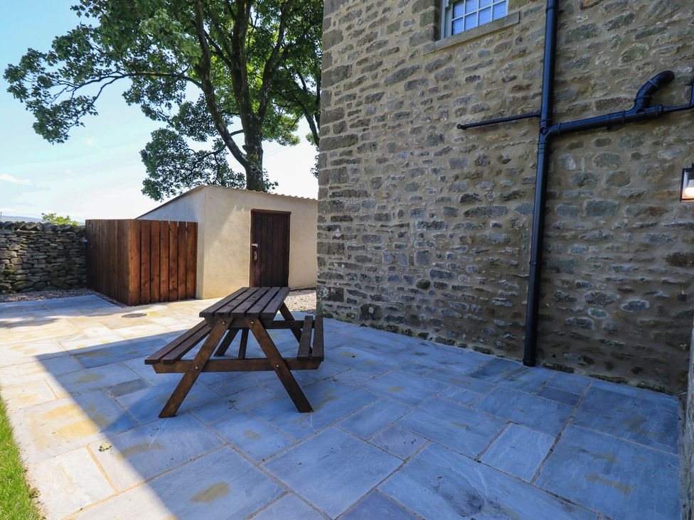 An outdoor patio with a table and benches at Ragged Hall Barn, Settle