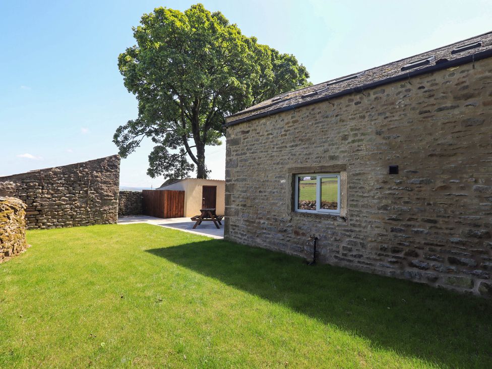 An outdoor area with a tree, stone wall, and a building at Ragged Hall Barn Settle
