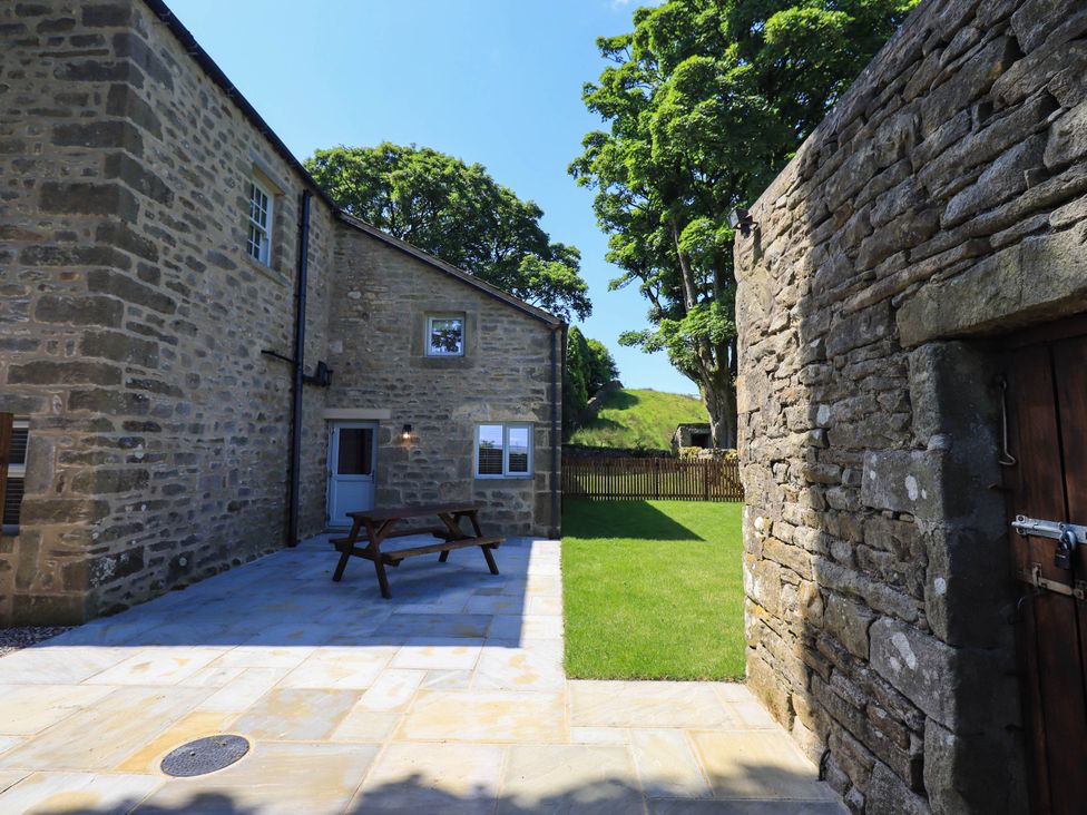 An outdoor area with a stone wall and seating at Ragged Hall Barn Settle