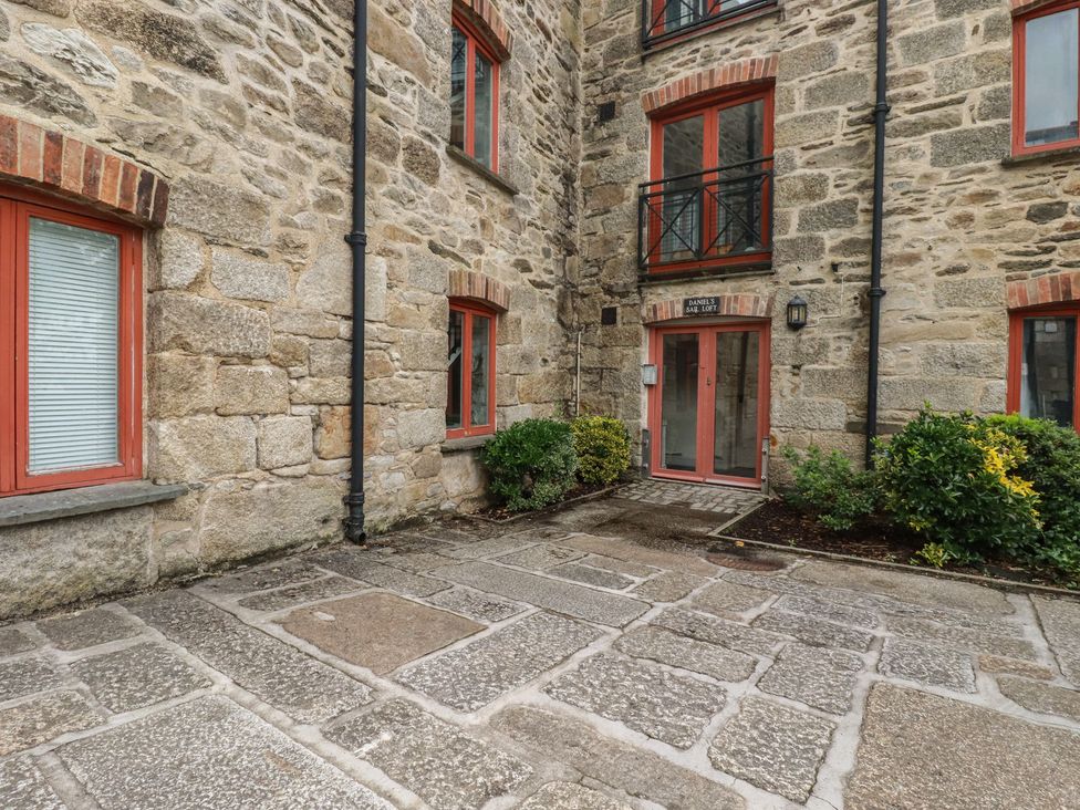 An outdoor area with stone wall and pathway at Daniel’s Sail Loft Penthouse in Penryn