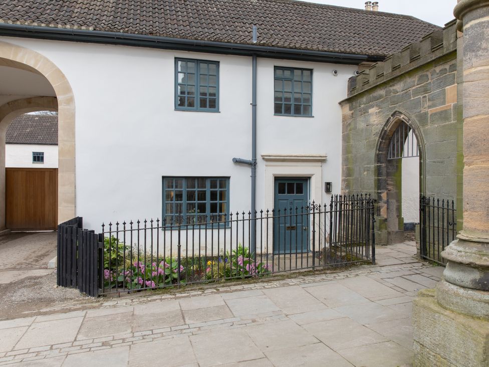 A house with a door and windows beside a stone wall at Bishop Lightfoot Cottage in Bishop Auckland