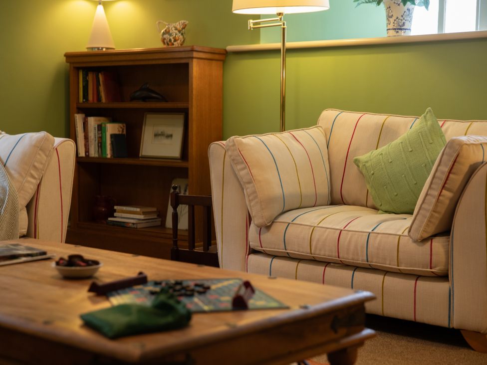 A living room with a sofa, table, and bookshelf at Bishop Lightfoot Cottage in Bishop Auckland