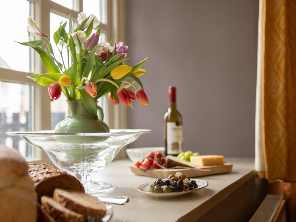 A dining table with tulips, cheese, wine, and fruits at Bishop Lightfoot Cottage in Bishop Auckland