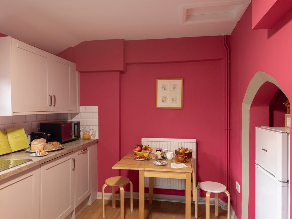 A kitchen with cabinets, table, chairs and food items at Bishop Lightfoot Cottage in Bishop Auckland