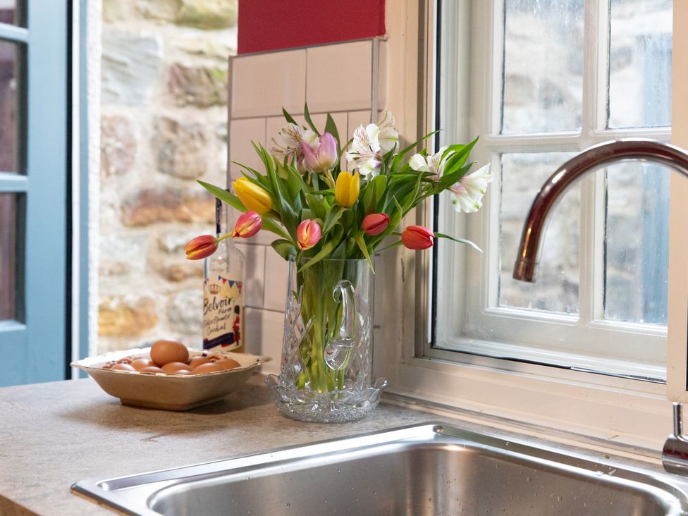 A kitchen with a bowl of eggs and flowers in a water jug at Bishop Lightfoot Cottage in Bishop Auckland