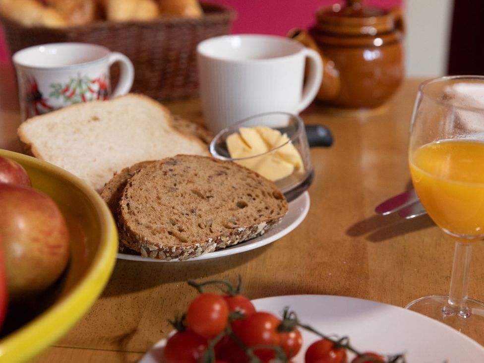 A dining table with bread, butter, orange juice, and apples at Bishop Lightfoot Cottage in Bishop Auckland