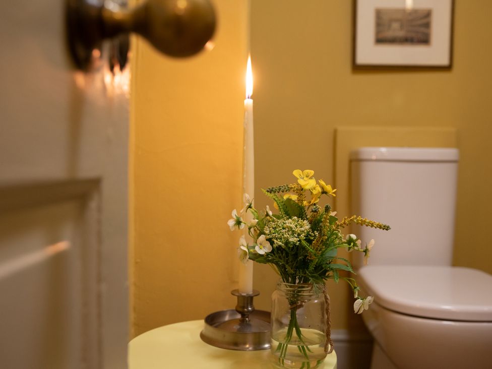 A bathroom with a candle, a flower arrangement, and a toilet at Bishop Lightfoot Cottage in Bishop Auckland